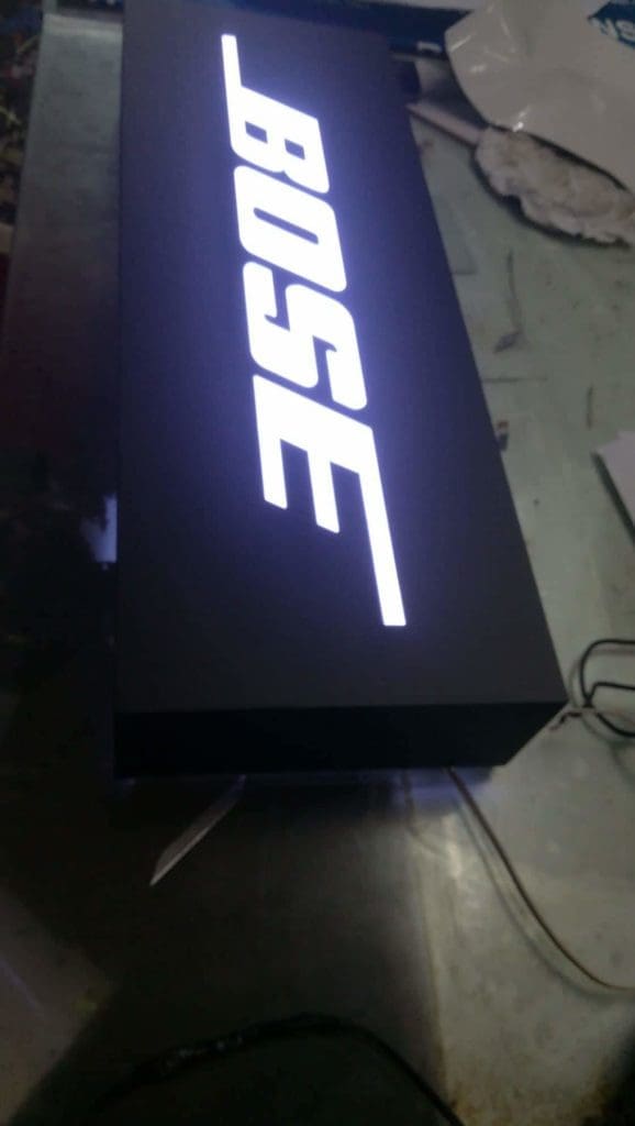 BOSE illuminated rectangular black metal signage on reflective surface in Makati, cords nearby, by M&G Global Ads.